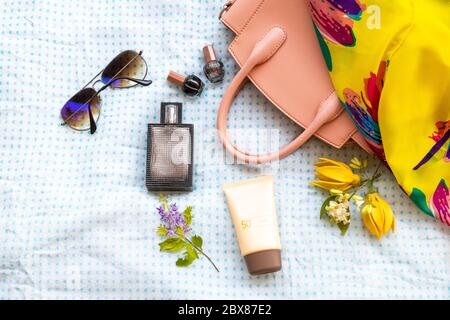 profumo, sciarpa gialla, occhiali da sole, smalto per unghie, crema solare spf50 e accessori rosa borsa di stile di vita donna relax disposizione piatto stile di posa Foto Stock