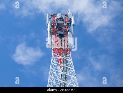 Parte superiore di una torre di antenna di rete cellulare autoportante in rosso e bianco metallico con più antenne contro cielo blu , Finlandia Foto Stock
