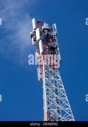 Parte superiore di una torre di antenna di rete cellulare autoportante in rosso e bianco metallico con più antenne contro cielo blu , Finlandia Foto Stock