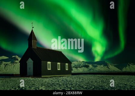 L'aurora boreale su una piccola chiesa nera. Aurora borealis su una delle chiese più semplici del mondo a Búðakirkja, Islanda Foto Stock