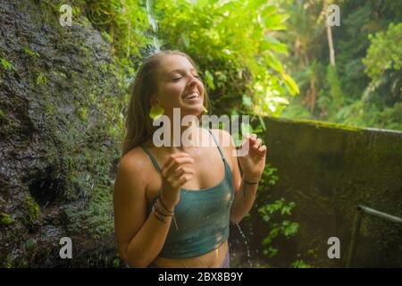 vacanze avventura ritratto stile di vita - giovane bella e felice donna prendendo doccia naturale dalla cascata nella giungla godendo la natura spensierata Foto Stock