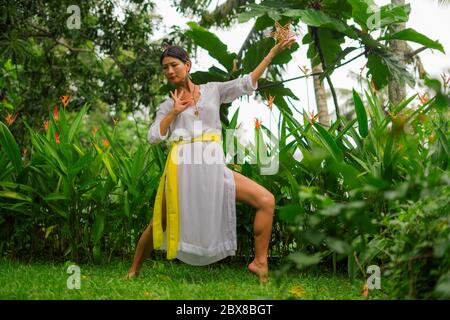 Connessione mente e corpo - bella e felice guaritrice donna asiatica tenendo incenso tazza facendo rituale tradizionale danza guarigione a verde foresta tropicale Foto Stock