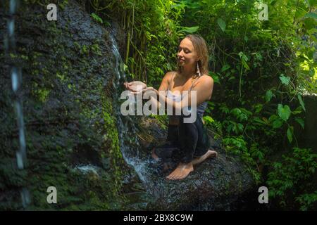 avventura all'aperto ritratto di giovane bella e felice donna nella roccia a foresta pluviale tropicale giocando con acqua fresca e spensierata godendo la natura du Foto Stock