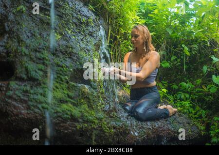 avventura all'aperto ritratto di giovane bella e felice donna nella roccia a foresta pluviale tropicale giocando con acqua fresca e spensierata godendo la natura du Foto Stock