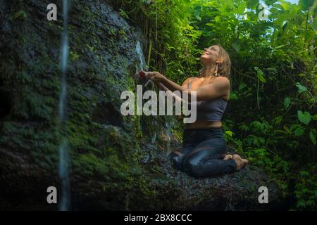 avventura all'aperto ritratto di giovane bella e felice donna nella roccia a foresta pluviale tropicale giocando con acqua fresca e spensierata godendo la natura du Foto Stock