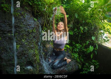 avventura all'aperto ritratto di giovane bella e felice donna nella roccia a foresta pluviale tropicale giocando con acqua fresca e spensierata godendo la natura du Foto Stock