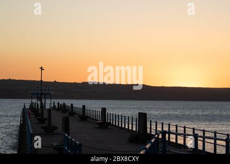 Weymouth, Regno Unito. 6 Giugno 2020. L'alba della mattina presto si innalora sullo Stone Pier a Weymouth Bay. Foto Stock