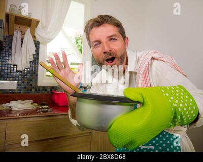 Chef marito . ritratto di stile di vita domestico felice e attraente 30s a  40s uomo in grembiule cucina e guanto che tiene piatto di cottura  degustazione e odore Foto stock - Alamy