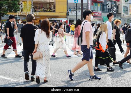 Persone che usano la grande corsa di scramble davanti alla Stazione di Shibuya. La gente indossa maschere facciali durante l'epidemia di coronavirus. Foto Stock