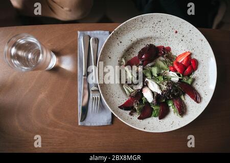 Primo piano foto di insalata con coltello e forchetta sul tavolo nel ristorante. Foto di insalata e bicchiere d'acqua sul tavolo al caffè Foto Stock