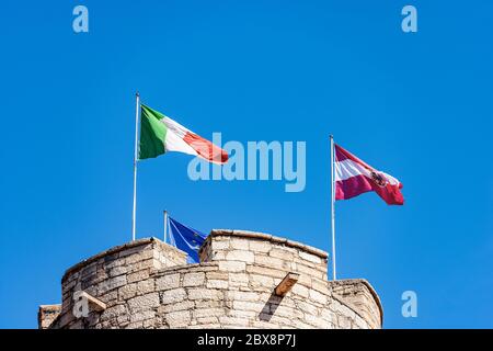 Bandiera italiana, austriaca ed europea sul castello. Castello del Buonconsiglio o Castelvecchio, torre circolare chiamata Torre di Augusto. Foto Stock