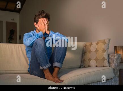 ritratto di stile di vita di giovane attraente e bello triste uomo latino seduta stanco e depresso a casa divano divano sensazione sopraffatta e preoccupato suffe Foto Stock