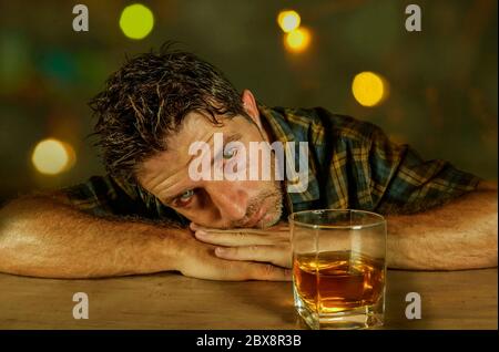 giovane attraente addict sprecato e depresso e l'uomo alcolico con vetro di whiskey pensieroso e triste fallendo tentazione di bere che cade int Foto Stock