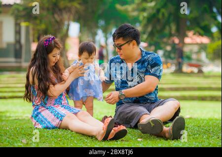 Giovane felice e amorevole famiglia giapponese asiatica con genitori e dolce figlia bambino al parco della città insieme con il padre che prende foto selfie con phon mobile Foto Stock
