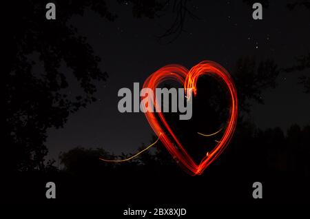 Cuore rosso su sfondo nero notte. Cuore disegnato dal fuoco su sfondo scuro. Amore, romantico e concetto di festa Foto Stock