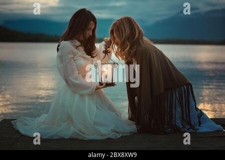 Belle donne che guardano in una lanterna calda luce. Paesaggio suggestivo Foto Stock