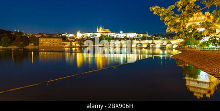 Praga di notte. Il Castello di Praga e il Ponte Carlo si riflettono nel fiume Moldava. Vista dall'argine Smetana. Praha, Repubblica Ceca. Foto Stock