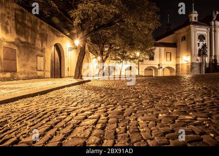 Strada acciottolata nella vecchia città medievale con case illuminate da lampioni vintage, Novy svet, Praga, Repubblica Ceca. Scatto notturno. Foto Stock