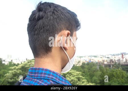 Vista posteriore di un giovane uomo che indossa una maschera. Sfondo della città. Foto Stock
