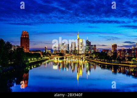 Splendida vista sullo skyline cittadino del centro di Francoforte sul meno, ponte con luci durante il tramonto all'ora blu, sera e notte. Finanza europea Foto Stock