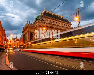 Serata al Teatro Nazionale e tram sfocato sul ponte, Praga, Repubblica Ceca. Scatto a lunga esposizione. Foto Stock