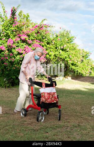 Anziana signora indossare maschera ottenere esercizio andare per una passeggiata in giardino Foto Stock