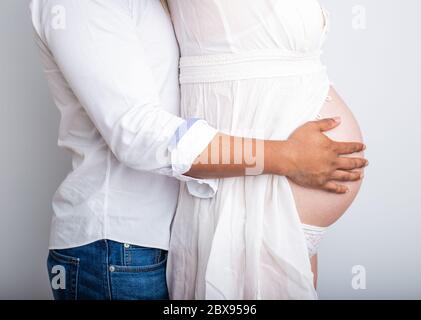 coppia incinta innamorato del ventre del bambino. Mani sullo stomaco bambino bump. Marito mano incinta pancia Foto Stock