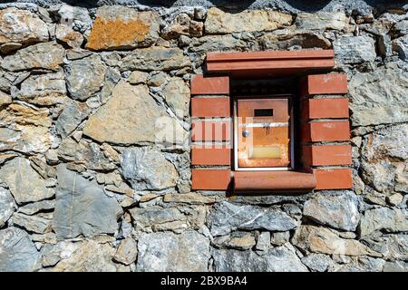 Primo piano di una vecchia e ruida mailbox in metallo incorporata nel muro di pietra. Liguria, Italia Foto Stock