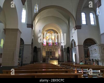 Vuota chiesa cattolica con una sola persona in preghiera Foto Stock