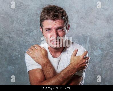 ritratto di uomo triste e depresso che abbracciava e si abbracciava disperato sentirsi frustrato e impotente nella depressione e tristezza espressione facciale Foto Stock