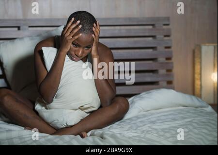 Giovane triste e depresso donna nera afro americana a letto insonne tarda notte sensazione disperata cercando preoccupato e ansioso sofferenza depressione probl Foto Stock