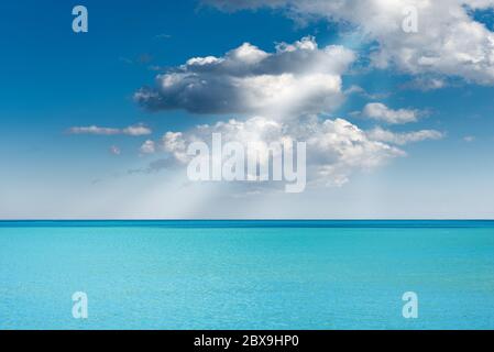 Mare turchese con cielo blu, nuvole e raggi solari, Mar Mediterraneo, Italia, Europa Foto Stock
