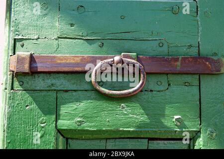 Chiusura di una vecchia porta di legno verde con un dispositivo di chiusura in ferro arrugginito. Veneto, Italia, Europa Foto Stock