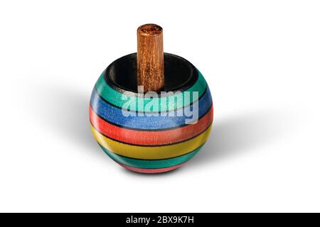 Primo piano di una piccola parte superiore rotante in legno multicolore su sfondo bianco con ombre chiare Foto Stock