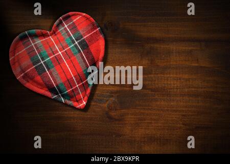 Primo piano di una forma a cuore in tessuto su uno sfondo di legno scuro con spazio per la copia Foto Stock