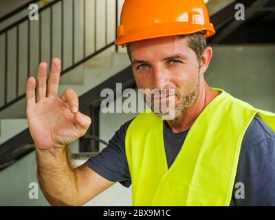 operaio di costruzione del collare blu. Ritratto aziendale di giovane attraente e felice costruttore uomo o costruttore in posa sicuro sorridente costruzione Foto Stock
