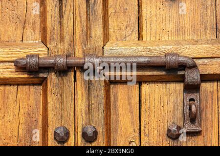 Primo piano di una vecchia porta in legno con un grande chiavistello in ferro battuto e borchie. Provincia di Verona, Veneto, Italia, Europa Foto Stock