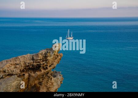 Vista sul mare dalle rocce su una barca a vela Foto Stock