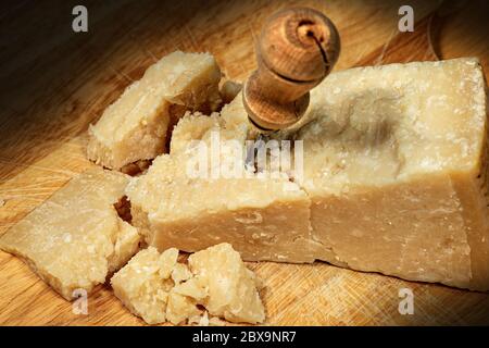 Primo piano di parmigiano su un tagliere di legno con coltello Foto Stock