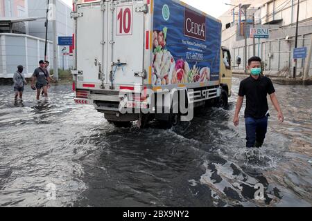 Giacarta, Indonesia. 06 giugno 2020. Un giovane uomo che indossa una maschera facciale è visto camminare attraverso una strada inondata di rubini a Jakarta.Rob inondazioni in Jarkata, questo è un fenomeno in cui l'acqua di mare sta traboccando nella terraferma. Può anche essere interpretato come un pozze d'acqua su terra costiera che si verifica quando le acque maree sono alte così infonderà parti della pianura costiera. Credit: SOPA Images Limited/Alamy Live News Foto Stock