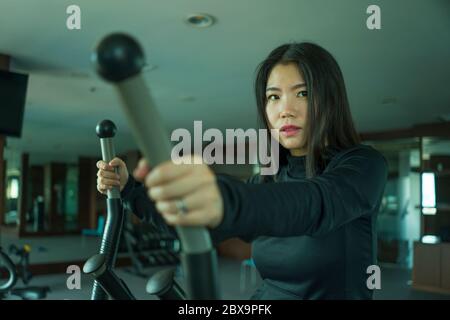 Giovane attraente e adatta donna Asiatica Coreana facendo l'allenamento in corsa alla palestra dell'hotel o al club fitness che fa jogging nella pedana mobile allenandosi duramente nello stile di vita sano Foto Stock