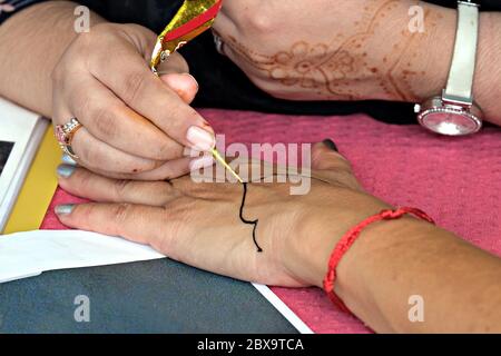 Artista che applica il tatuaggio henné alle mani delle donne durante il festival orientale della cultura Foto Stock