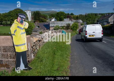 Taglio di cartone di un poliziotto che tiene una pistola ad alta velocità per aiutare il traffico lento sull'avvicinamento ad un villaggio. Cumbria, Regno Unito. Foto Stock