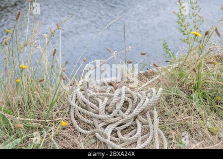 Funi ormeggio barche avvolte sul lato della banchina di un fiume. Nautica da metafora, attività all'aperto, vela. Foto Stock