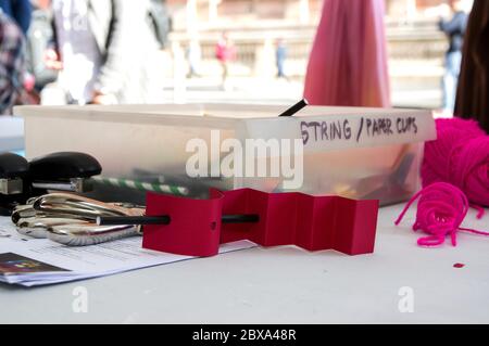 scatola di plastica con etichetta stringa e tagli di carta in uno stallino esterno con perforatori e carta piegatrice in primo piano Foto Stock