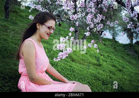 Ragazza in campagna con un vestito rosa e circondata da mandorli. Foto Stock