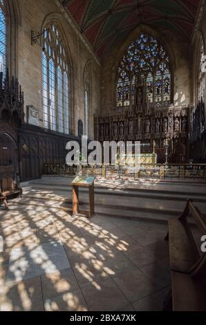 Interno di alto alter nella chiesa di St. Botolph a Boston, Lincolnshire con luce solare che scorre attraverso le finestre che gettano ombre modellate sul pavimento. Foto Stock