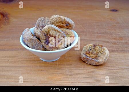 Piatto di fichi secchi organici e fichi secchi versato su sfondo di legno Foto Stock