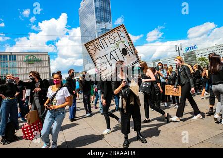 Il protestante con maschera facciale e cartello 'stazione di pulizia' offre un disinfettante per le mani a una protesta Black Lives Matter ad Alexanderplatz Berlin, Germania. Foto Stock