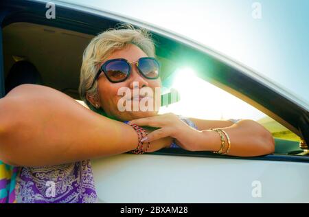 Ritratto di stile di vita attraente e felice donna indonesiana asiatica di mezza età 40 o 50 anni con capelli grigi e bel sorriso seduto in macchina enjoyi Foto Stock